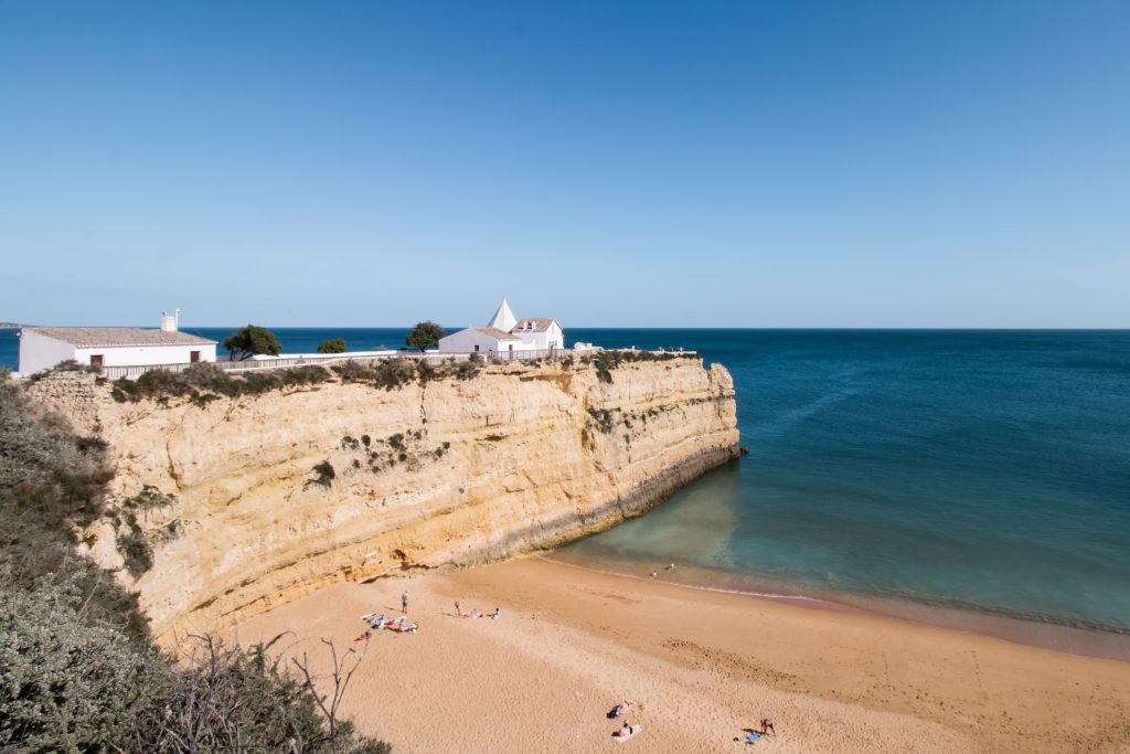 Praia da Senhora da Rocha e a capela sobre a falésia, em Porches